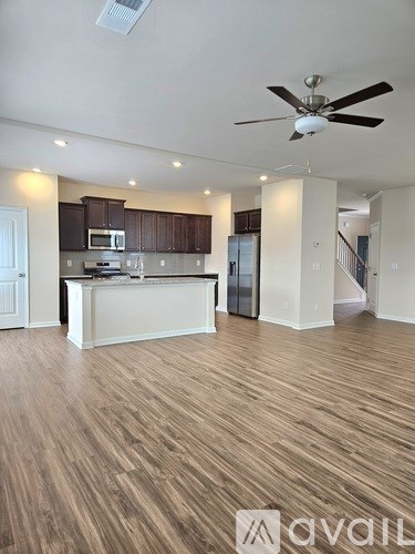 A spacious kitchen with wooden floors and a ceiling fan.