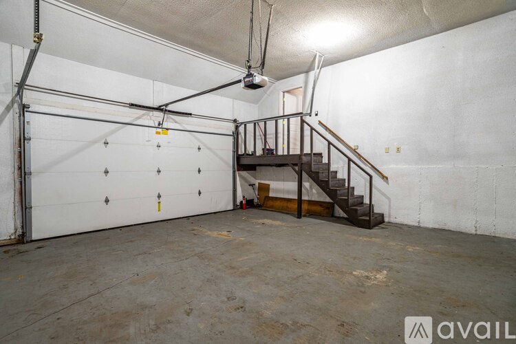 A spacious garage with a staircase and a ceiling fan.
