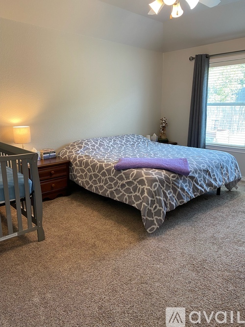 A bedroom with a bed, a nightstand, and a crib.