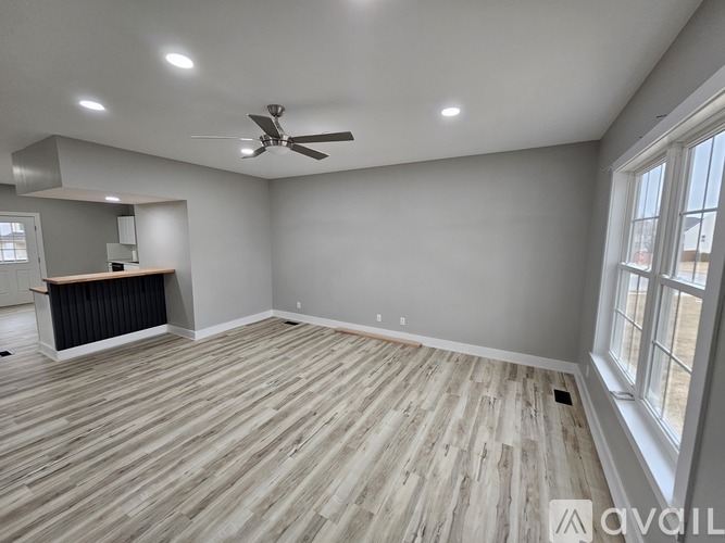 A spacious room with wooden flooring and a ceiling fan.