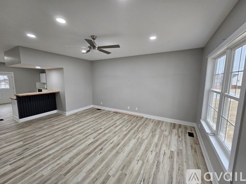 A spacious room with wooden flooring and a ceiling fan.