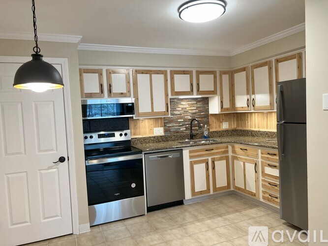 A kitchen with wooden cabinets and a black fridge.