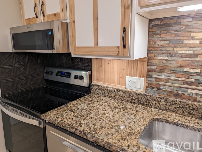 A kitchen with granite countertops and a stone backsplash.