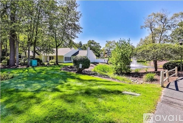 A house with a well-maintained lawn and trees in the background.