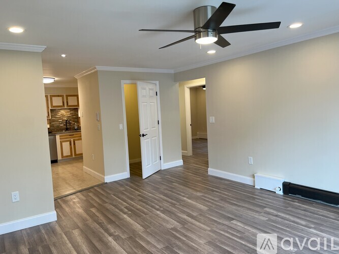 A room with a ceiling fan and wooden flooring.