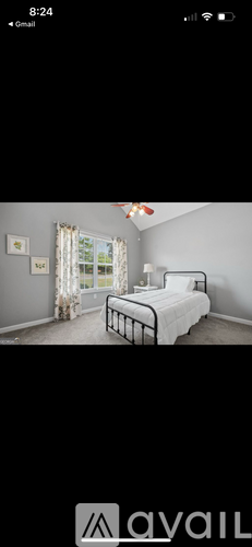 A bedroom with a bed, nightstand, and window with curtains.