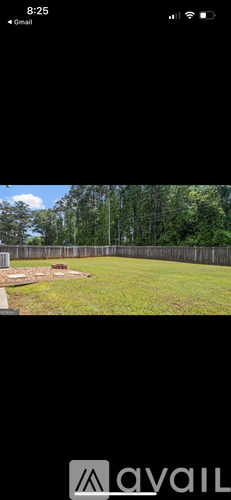 A grassy field with a fence and trees in the background.