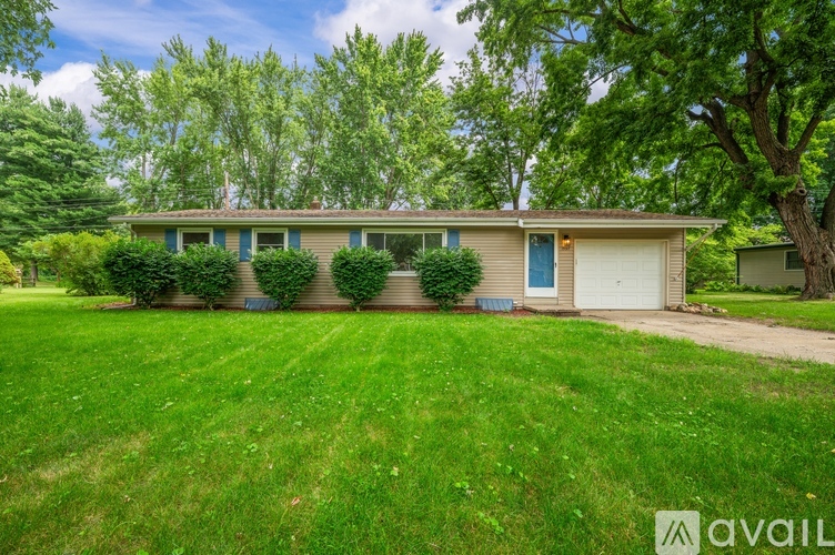A house with a blue door is surrounded by greenery.