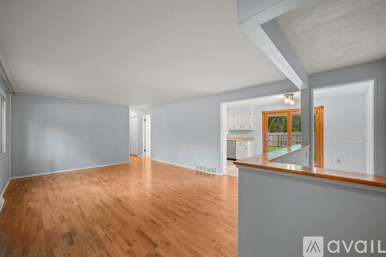 A spacious room with wooden flooring and a large window.