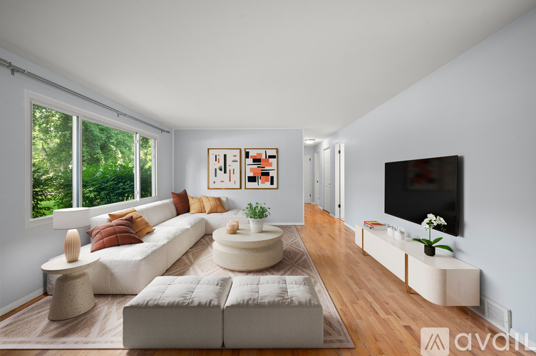 A modern living room with a white sofa, a coffee table, and a flat-screen TV.