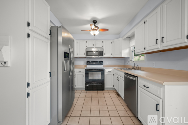 A kitchen with white cabinets and a tile floor.