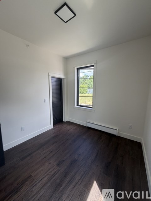 A room with a window and wooden flooring.