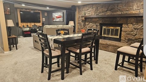 A dining room with a stone fireplace and a TV mounted on the wall.