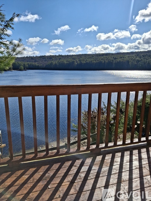 A wooden deck overlooks a lake with trees and a cloudy sky.