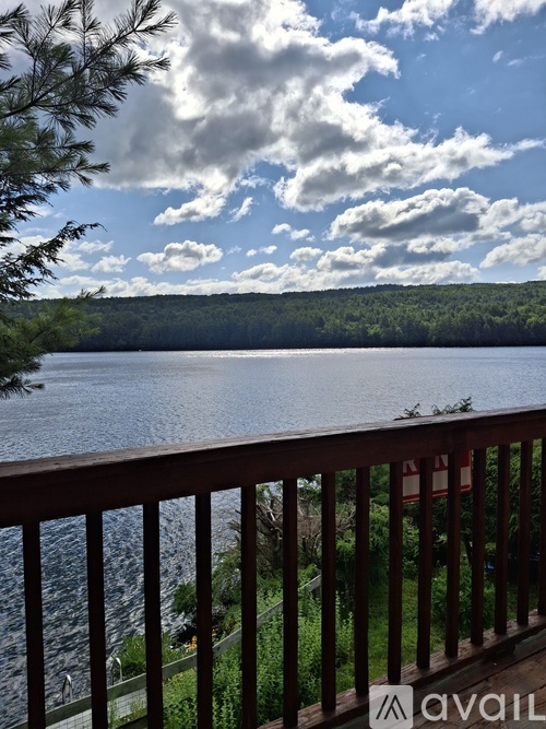A wooden deck overlooks a lake with a cloudy sky above.