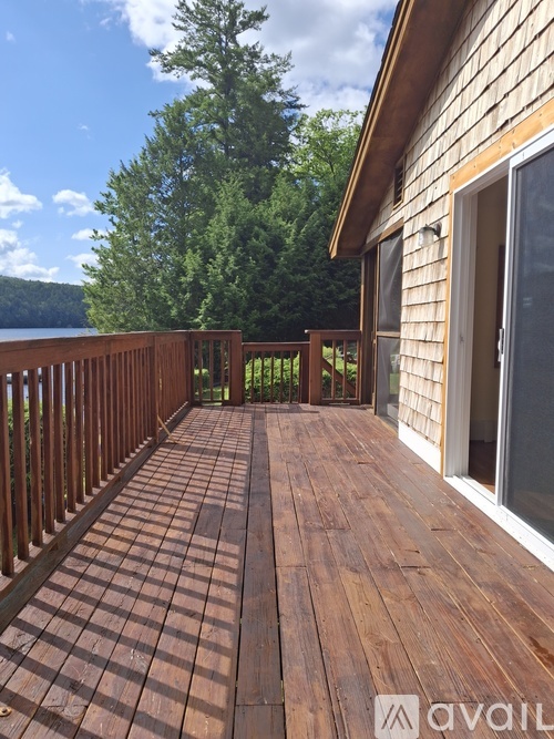 A wooden deck with a railing and a view of a lake and trees.