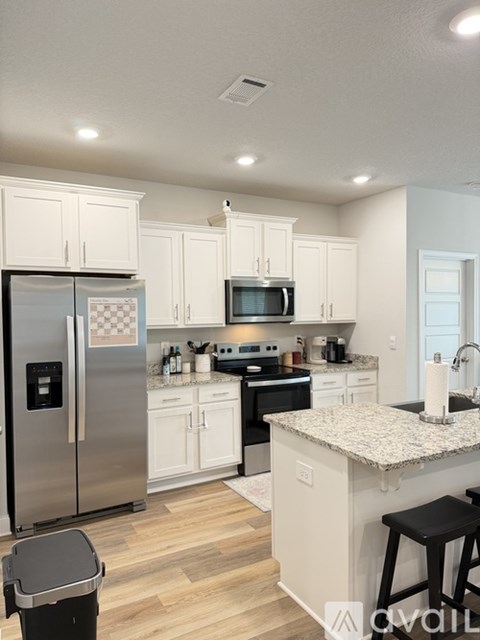 A kitchen with white cabinets and a granite countertop.