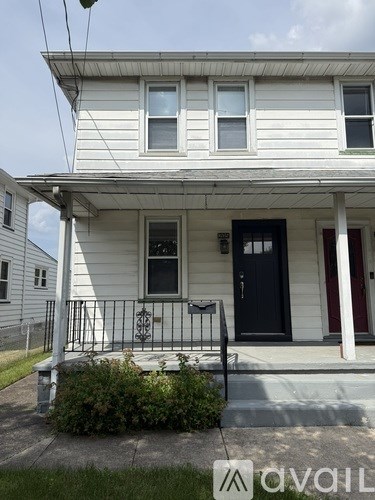A white house with a black front door and red door frame.