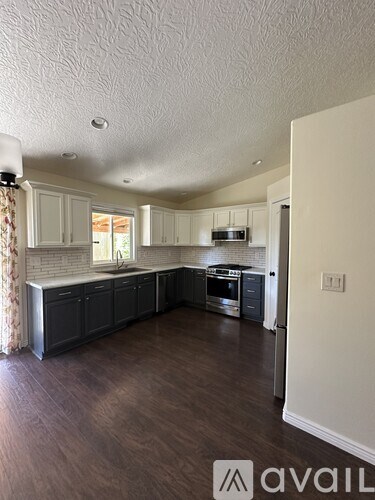 A kitchen with dark wood floors and white walls.