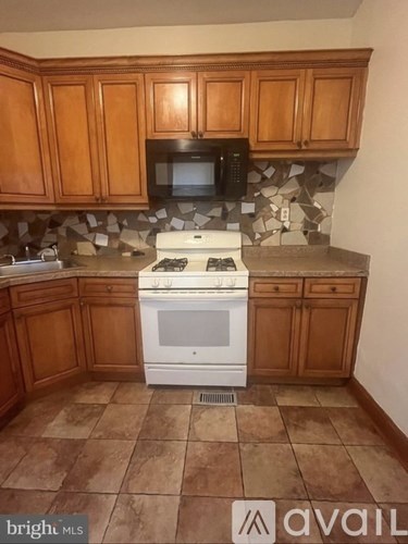 A kitchen with a white stove top oven and a black microwave above it.