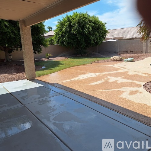 A patio with a table and chairs is shown with a view of a backyard.