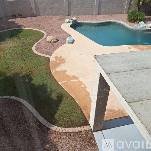 A pool with a concrete patio and a grassy area.