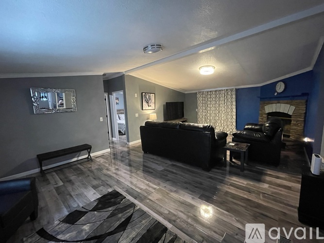 A living room with a black couch and a wooden floor.