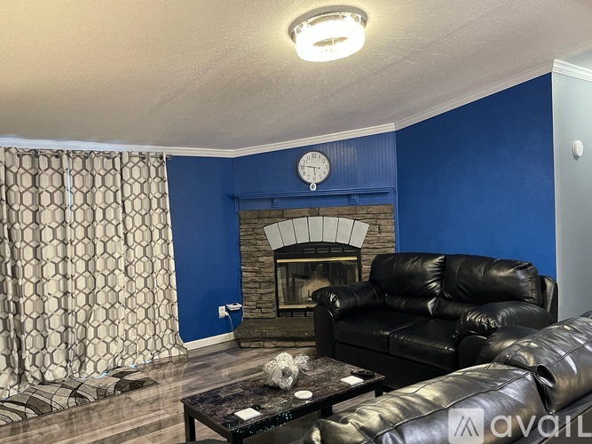 A living room with a black leather couch and a fireplace.