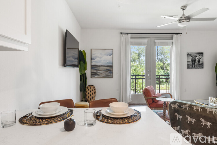 A dining room with a table set for two and a flat screen TV mounted on the wall.