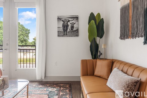 A living room with a tan couch and a framed black and white photo of two cows on the wall.