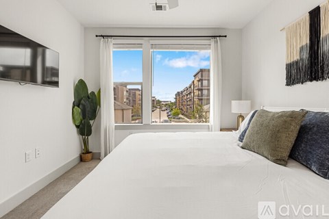 A bedroom with a large bed and a view of the city through the window.