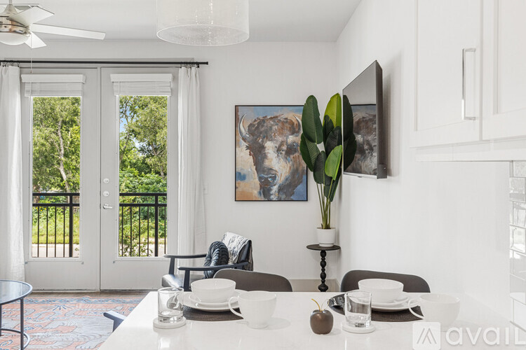 A dining room with a table set for two and a painting of a bull on the wall.