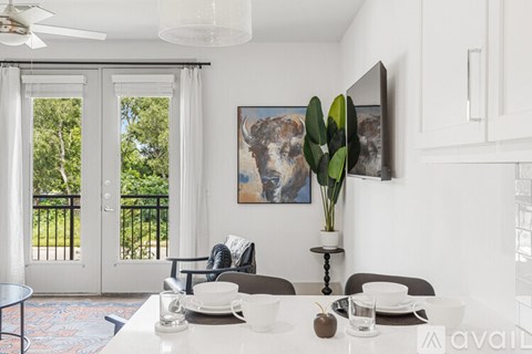 A dining room with a table set for two and a painting of a bull on the wall.