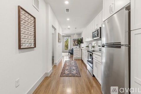 A modern kitchen with a stainless steel refrigerator and wooden flooring.
