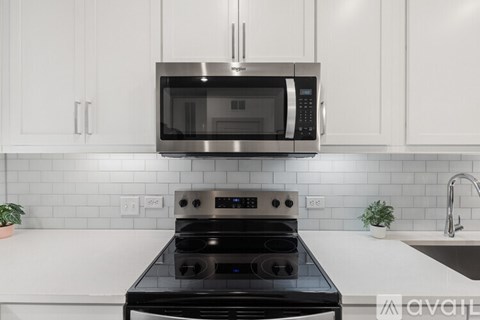 A modern kitchen with a black stove top oven and a microwave above it.
