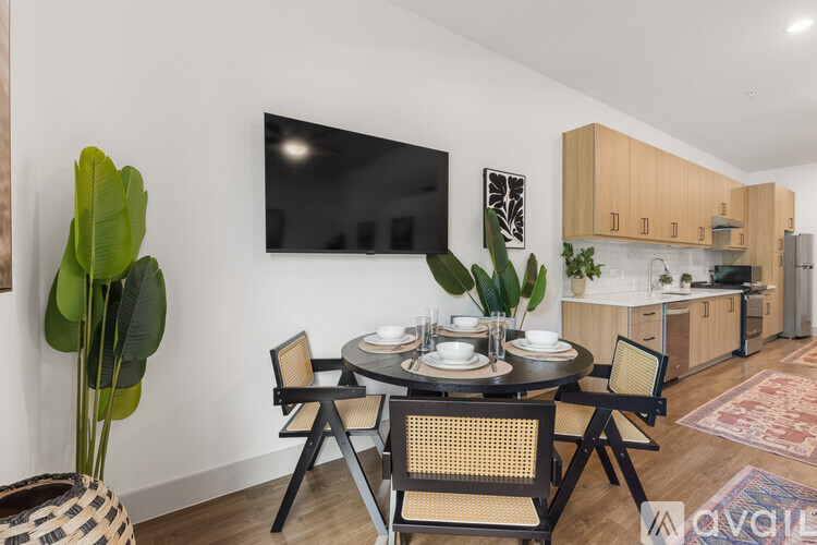 A modern dining room with a round table set for two and a flat screen TV mounted on the wall.