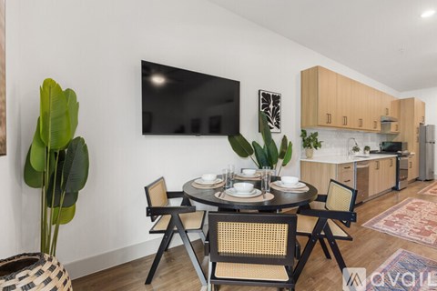 A modern dining room with a round table set for two and a flat screen TV mounted on the wall.