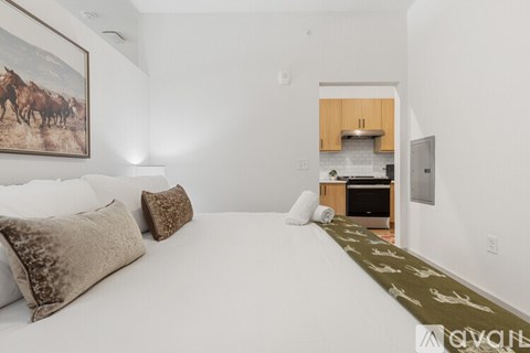 A bedroom with a large bed and a painting of horses on the wall.