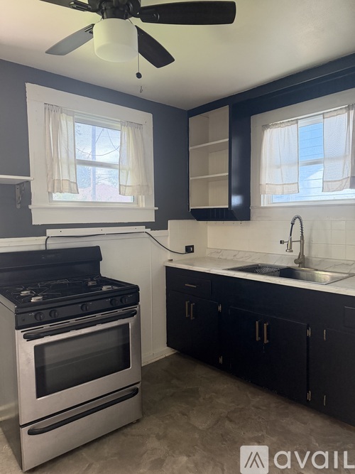 A kitchen with a black stove top oven and a black fan ceiling light.