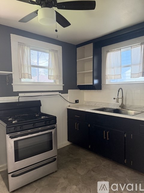 A kitchen with a black stove top oven and a black fan ceiling light.