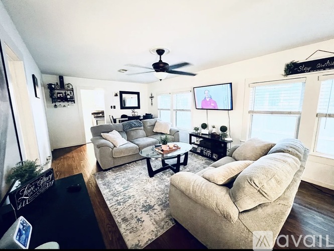 A living room with a beige couch, a coffee table, and a ceiling fan.