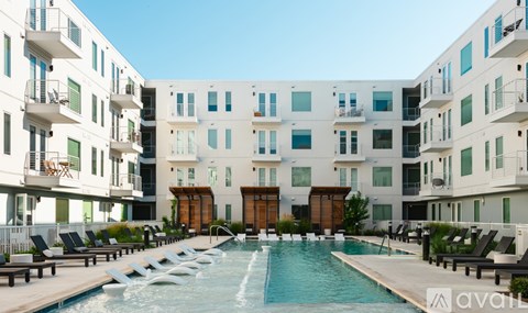 A large swimming pool in front of a white building with a balcony.