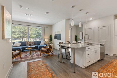 A modern kitchen and living room with a large window and a rug.