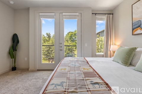 A bedroom with a large bed and a view of trees through the sliding glass doors.