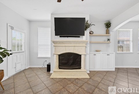 A living room with a fireplace and a television above it.