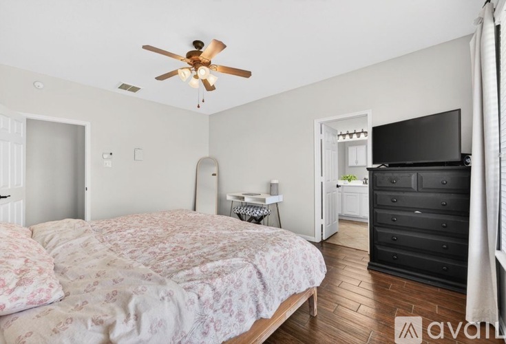 A bedroom with a bed, dresser, and a ceiling fan.
