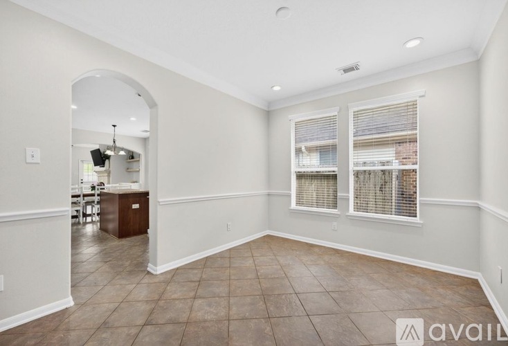 A spacious room with tiled flooring and a large arched doorway leading to another room.