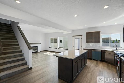 A modern kitchen with dark wood cabinets and a staircase.