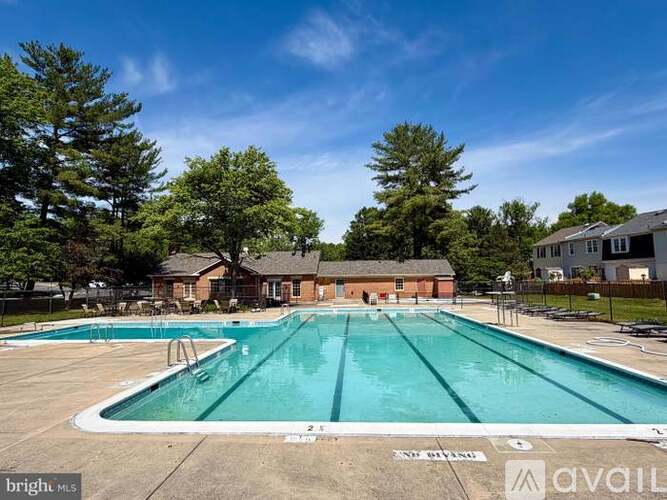 A large outdoor swimming pool surrounded by trees and a building in the background.