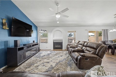 A living room with a brown leather couch and a fireplace.